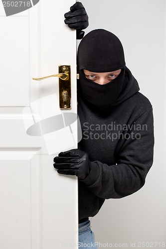 Image of Burglar sneaking in a open house door