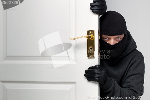 Image of Burglar sneaking in a open house door