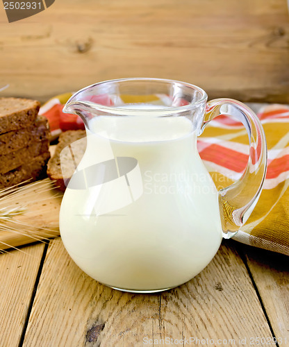 Image of Milk in a jug with rye bread and red napkin