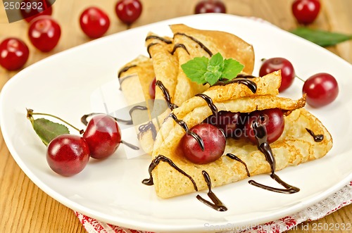 Image of Pancakes with cherry and chocolate syrup on the board