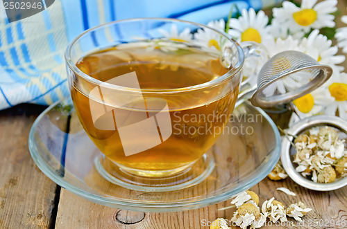 Image of Herbal chamomile tea dry in a strainer with a glass cup