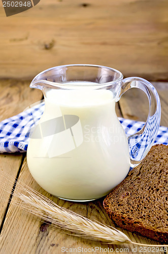 Image of Milk in a jug with rye bread and a blue cloth