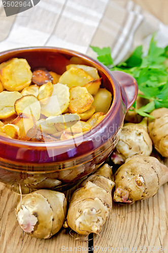 Image of Jerusalem artichokes roasted in a clay pot on a board