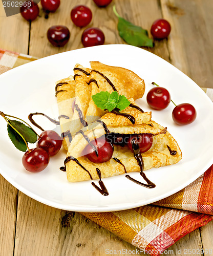 Image of Pancakes with cherry and chocolate syrup with a napkin