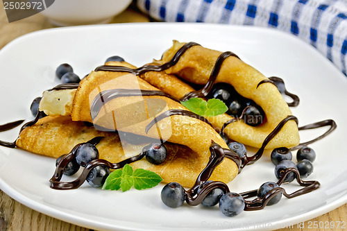 Image of Pancakes with blueberries and chocolate syrup on the board