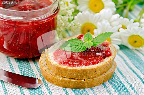 Image of Bread with strawberry jam and daisies on a napkin