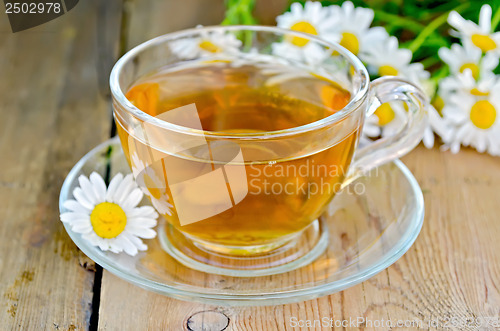 Image of Herbal chamomile tea in a glass cup on a board