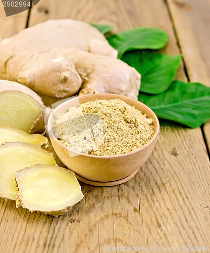 Image of Ginger powder in a bowl with the root and leaves