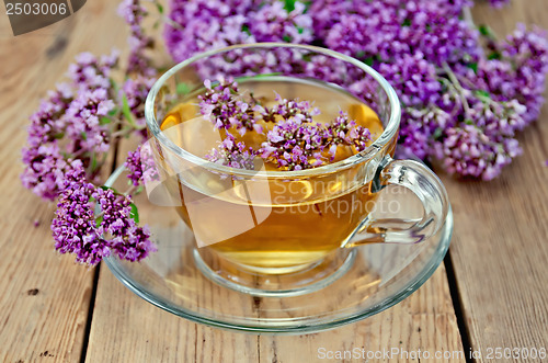 Image of Herbal tea from oregano in a glass cup on a board