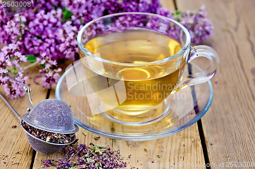 Image of Herbal tea of oregano with strainer in a glass cup