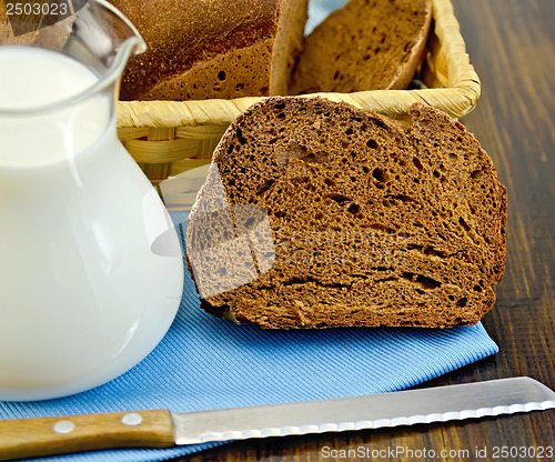 Image of Rye homemade bread with milk and a knife on a board