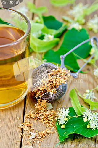 Image of Herbal tea from linden flowers in a mug with a strainer on the b