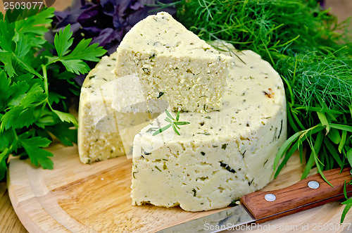 Image of Cheese round homemade with herbs and knife on board