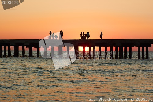 Image of People on the old sea pier during sunset