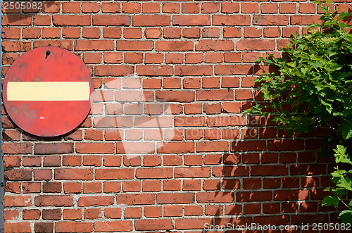 Image of no entry road sign on a brick wall and bush