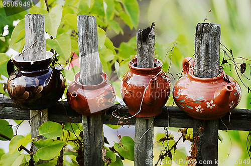 Image of four ceramic teapot on a wooden fence