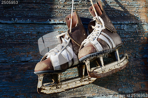 Image of vintage pair of mens  ice skates hanging on a wooden wall with c