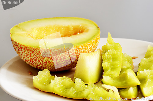 Image of half of ripe melonand peels on a plate, still life