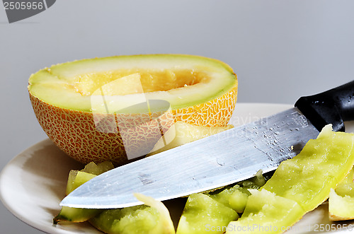 Image of still life, half of ripe melon, knife and peels on a plate