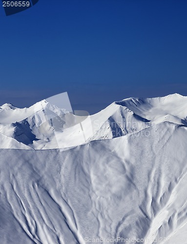 Image of Off-piste slope with traces of skis and snowboards in sun day