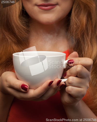 Image of woman holding hot cup and smiles