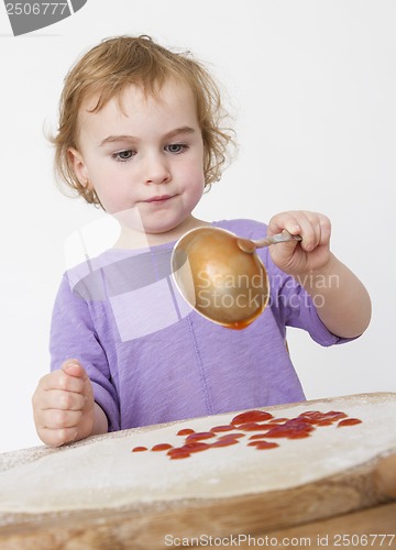 Image of child putting sieved tomatoes on dough