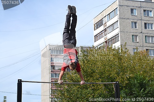 Image of The man goes in for sports on a horizontal bar in a house yard