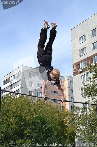 Image of The man goes in for sports on a horizontal bar in a house yard