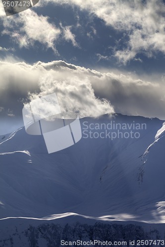 Image of Evening mountains with sunlit clouds