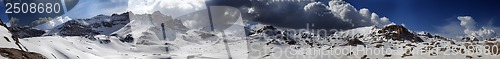 Image of Panorama of snowy winter mountains with blue sky and dark clouds