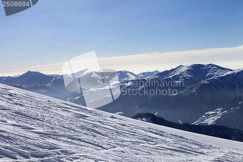 Image of Ski slope with trace of ski, snowboards and mountains in haze