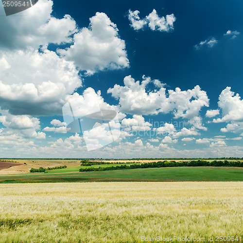 Image of deep blue sky with clouds and green landscape