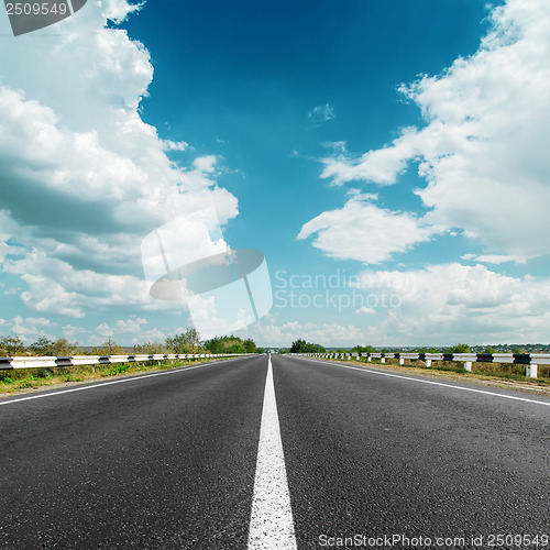 Image of white line on asphalt road and clouds over it