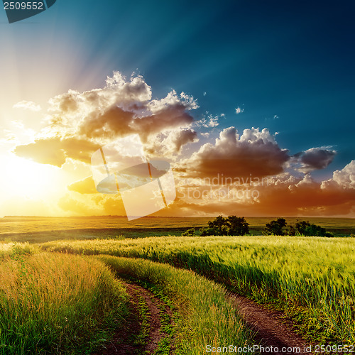 Image of dramatic sunset over road in fields