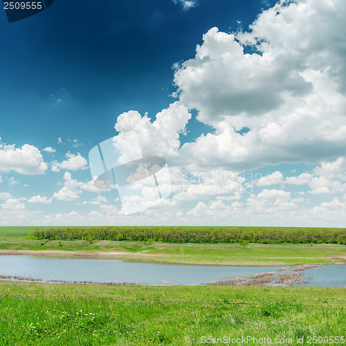 Image of river in green grass and clouds in blue sky