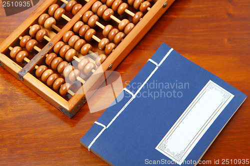 Image of Chinese book , abacus and writing brush on the table