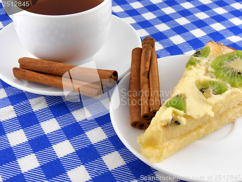 Image of A cup of tea and a piece of tasty creamy cake with cinnamon