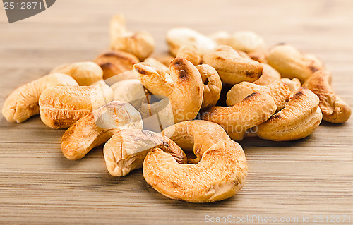 Image of A handful of roasted cashew nuts on wood background