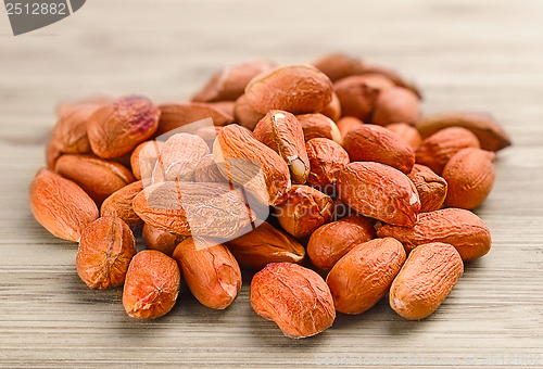 Image of heap of raw peanuts on the wooden background