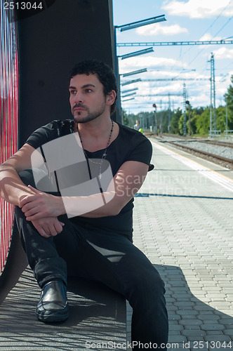 Image of Handsome man sitting on platform