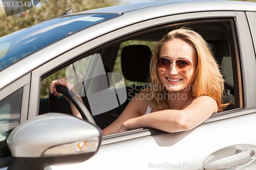 Image of young attractive happy woman sitting in car summertime