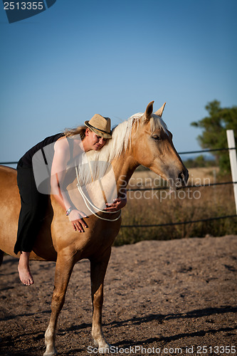 Image of young woman training horse outside in summer