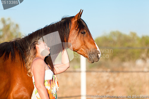 Image of young woman training horse outside in summer