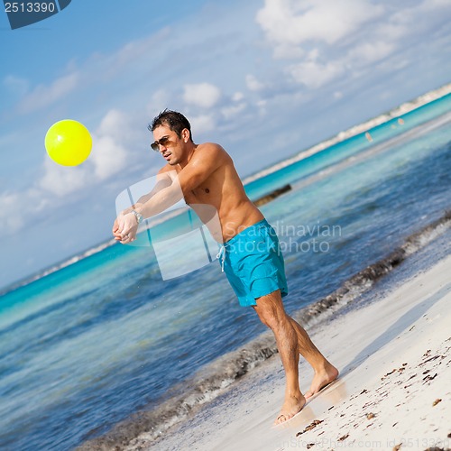 Image of happy young adult man playing beach ball in summer 