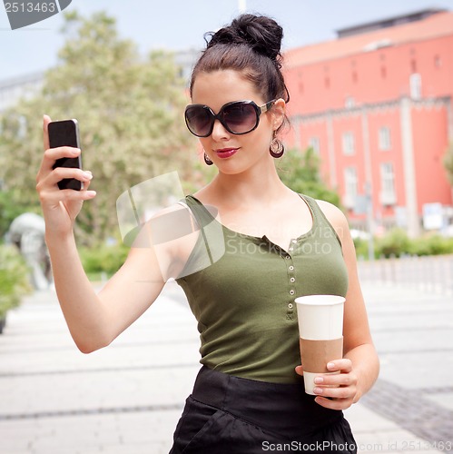 Image of attractive young woman with smartphone and sunglasses outdoor