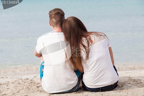 Image of romantic young couple sitting on the beach in summer
