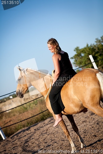 Image of young woman training horse outside in summer