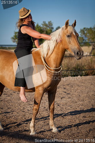 Image of young woman training horse outside in summer