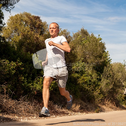 Image of athletic man runner jogging in nature outdoor