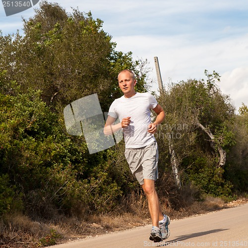 Image of athletic man runner jogging in nature outdoor